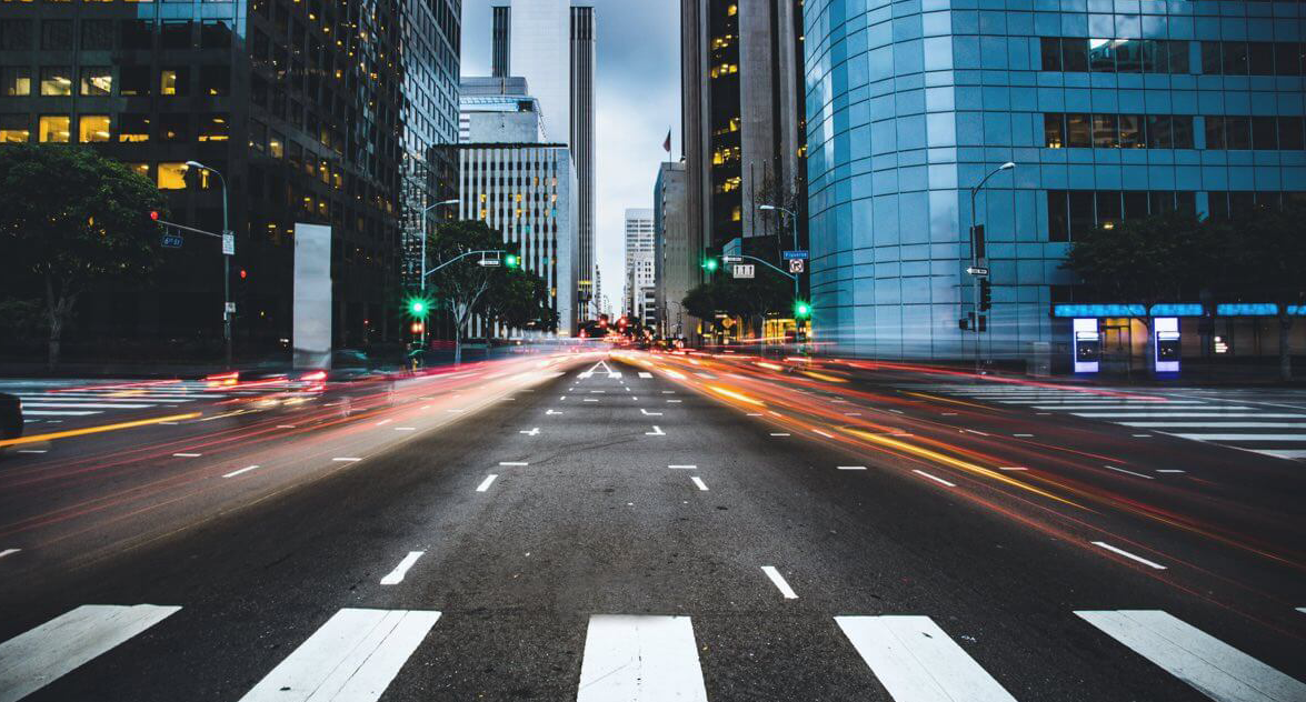 A city intersection at dusk — roads, power, water and telecom all converging