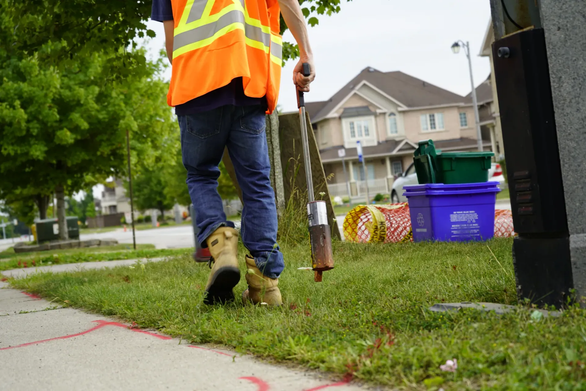 A utility locator sweeping a residential lawn with a locating wand