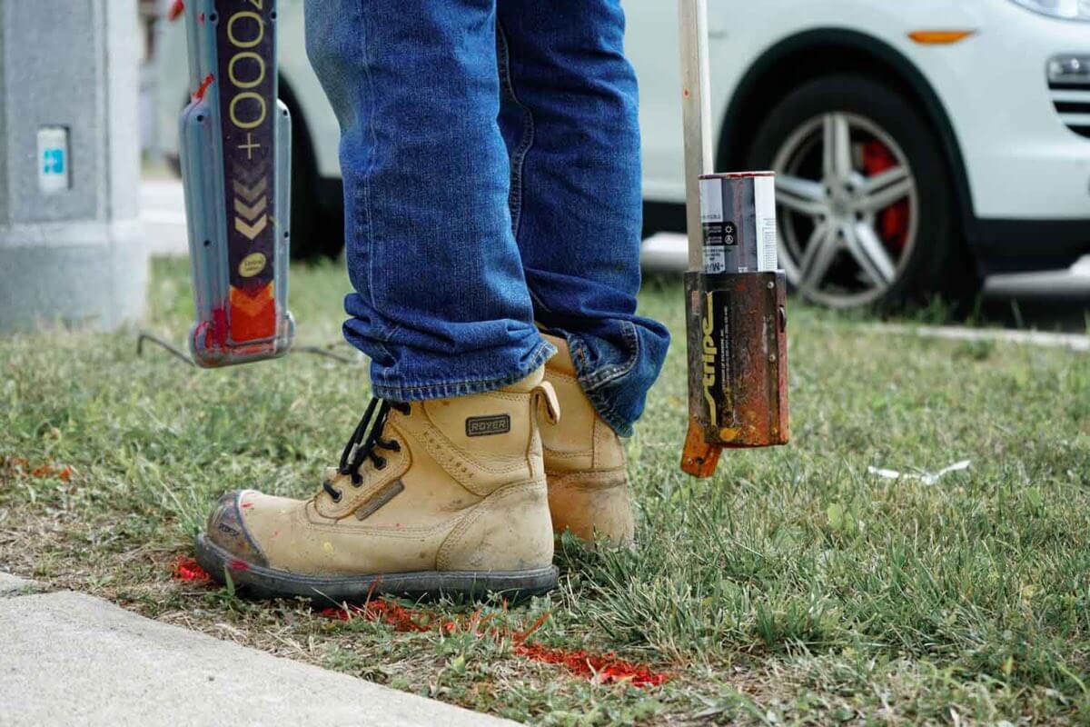 A utility locator's boots beside fresh locate marks
